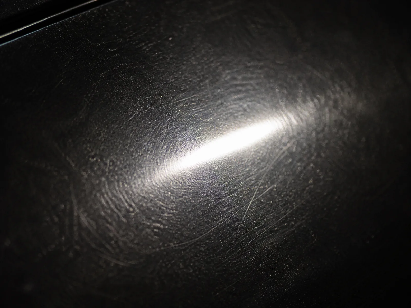 Schwarzer Autolack mit feinen Kratzern und matter Oberfläche